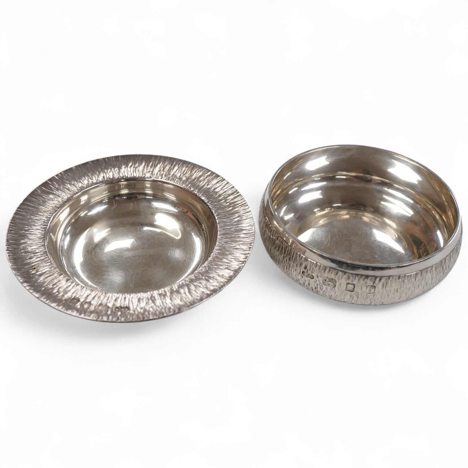 An Elizabeth II bark effect silver shallow bowl by Adrian Gerald Benney, London, 1974, top diameter 9cm, together with a similar shallow dish, by Adrian Gerald Benney, London, 1974, diameter 11.9cm, 8.8oz.